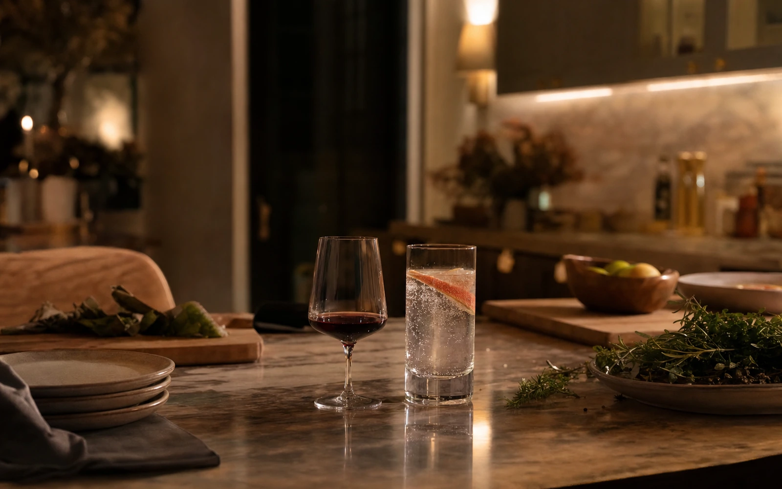 Warm kitchen island with a small glass of red wine beside a tall sparkling water.