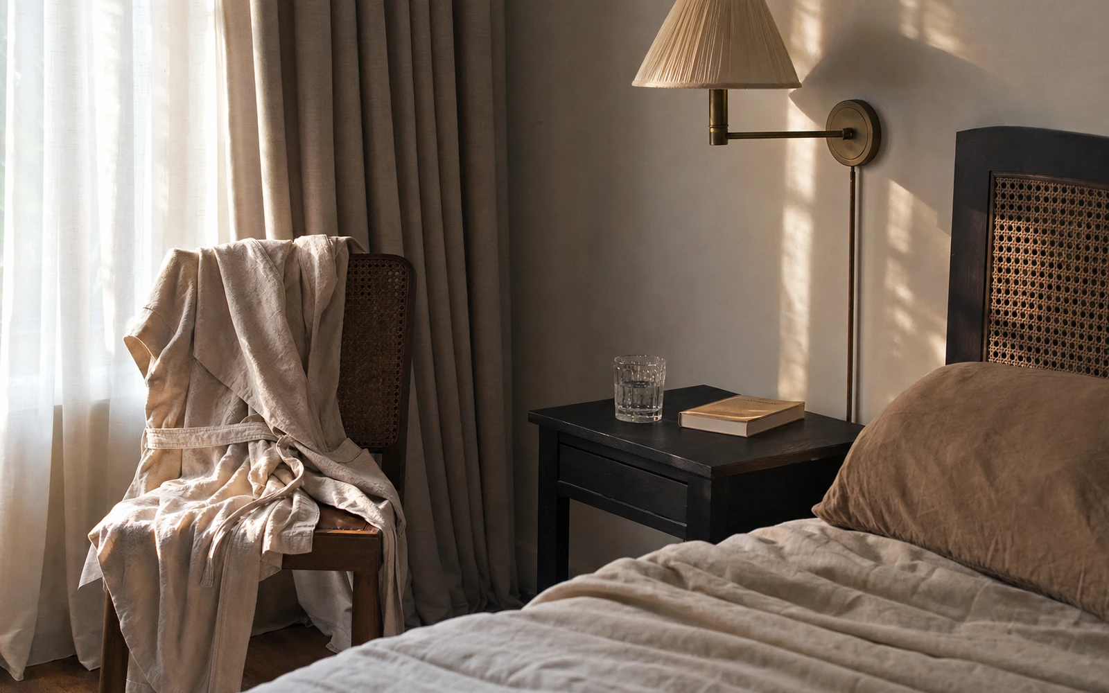 Sunlit bedroom with linen bedding and a quiet bedside table.