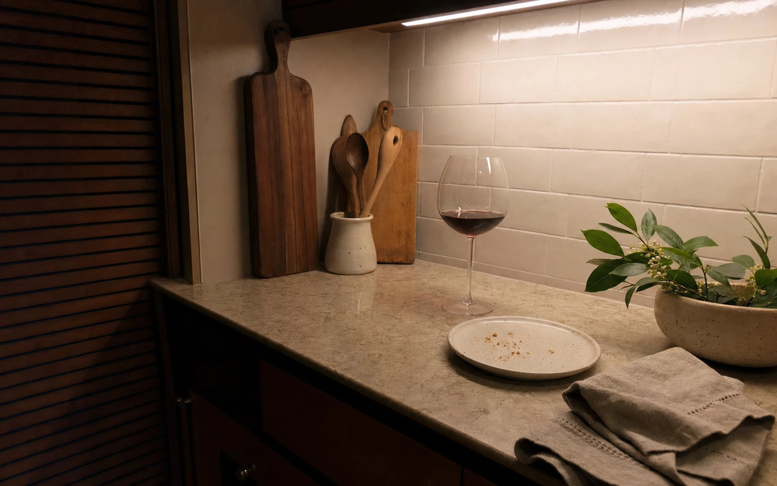 Evening kitchen counter after dinner with a wine glass and small plate.