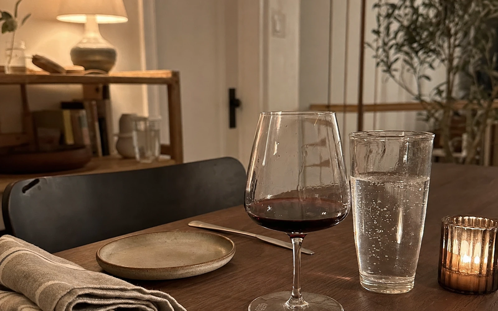 Dinner table at night with a glass of red wine next to a tall glass of water.