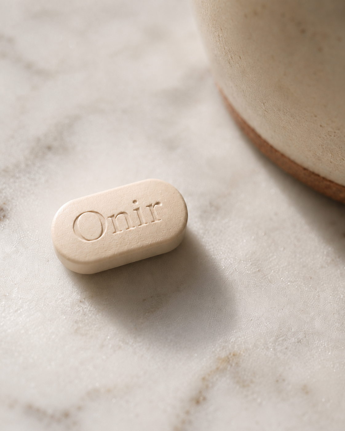 Close-up of a single Onir naltrexone tablet on marble — FDA-approved medication for alcohol use disorder